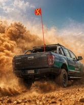 Off-road vehicle driving through sand with a vehicle safety flag on top